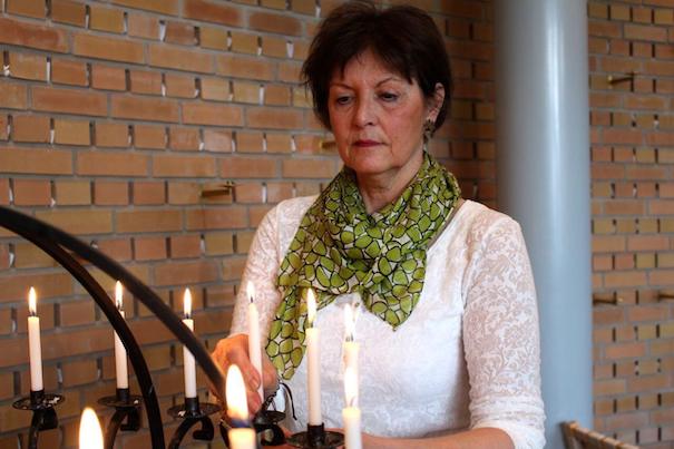 Bilde av Bente Ridder-Nielsen som tenner lys i et kapell