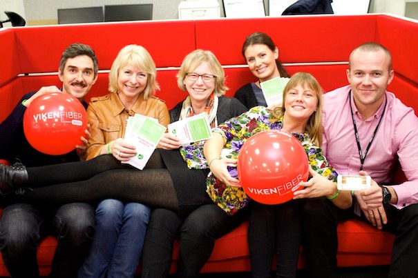 Bilde av ansatte i Viken Fiber og Stiftelsen Organdonasjon som sitter i en sofa. De holder ballonger og donorkort. 