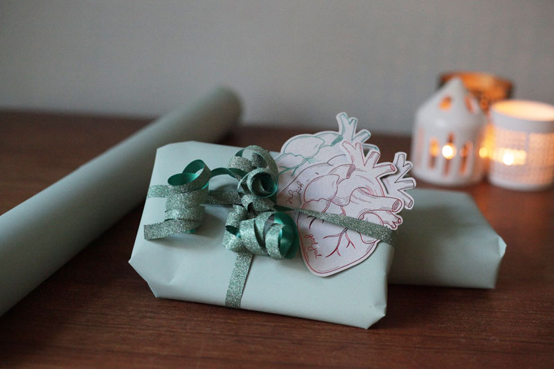 julegave med julekort på bord med stemningsfylte tente lys